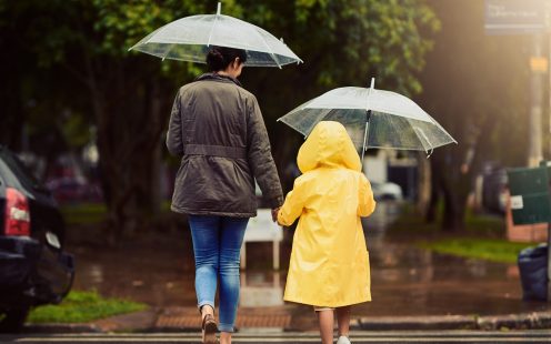 Rearview shot of an unrecognizable little boy and his mother holding hands and walking in the rain outside