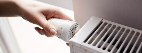 Closeup on woman's hand adjusting thermostat valve