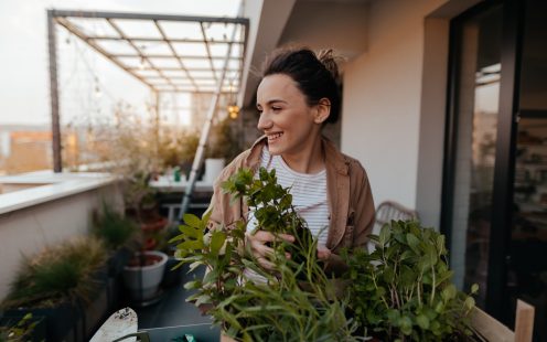 Young woman setting up and arranging greenery on her building terrace