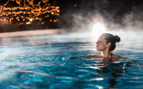 Beautiful woman swimming in a swimming pool with steam.