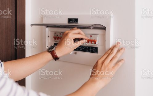 Circuit breaker board displays many switches. A finger is about to turn it back on